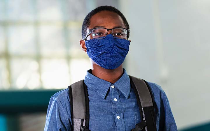 young boy wearing backpack and mask