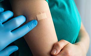 sterile gloved hand pressing down bandage on arm