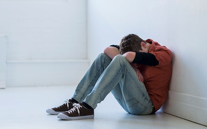 Older teenage boy sitting in hallway