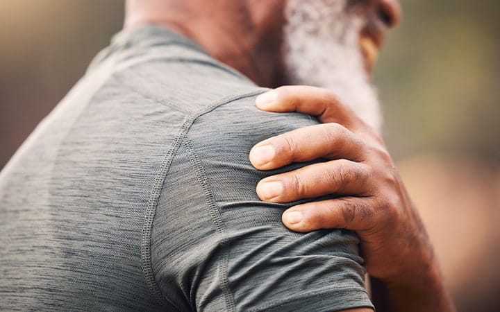 Older man clutching his painful shoulder muscle