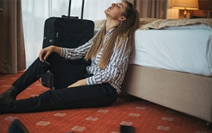Woman with luggage sitting on hotel room floor