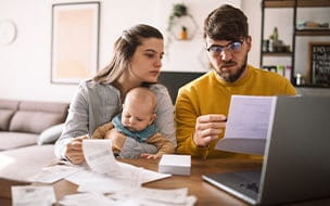 Young couple with baby reviews bills