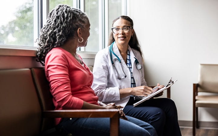 Female doctor talking with senior woman in waiting room