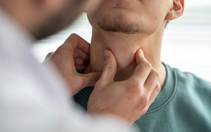 A doctor is examining a male patient's throat