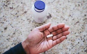 A woman holding a nutritional supplement capsule in the palm of her hand